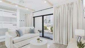 A modern living room with a white sofa, a round coffee table, and a view of a balcony with curtains. - Private Beach|Bikes|Pool|Next2Seaside (Santa Rosa Beach)