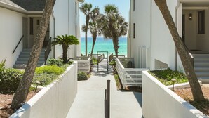 A pathway leading to a balcony with a view of the ocean, flanked by palm trees and white walls. - Private Beach|Bikes|Pool|Next2Seaside (Santa Rosa Beach)
