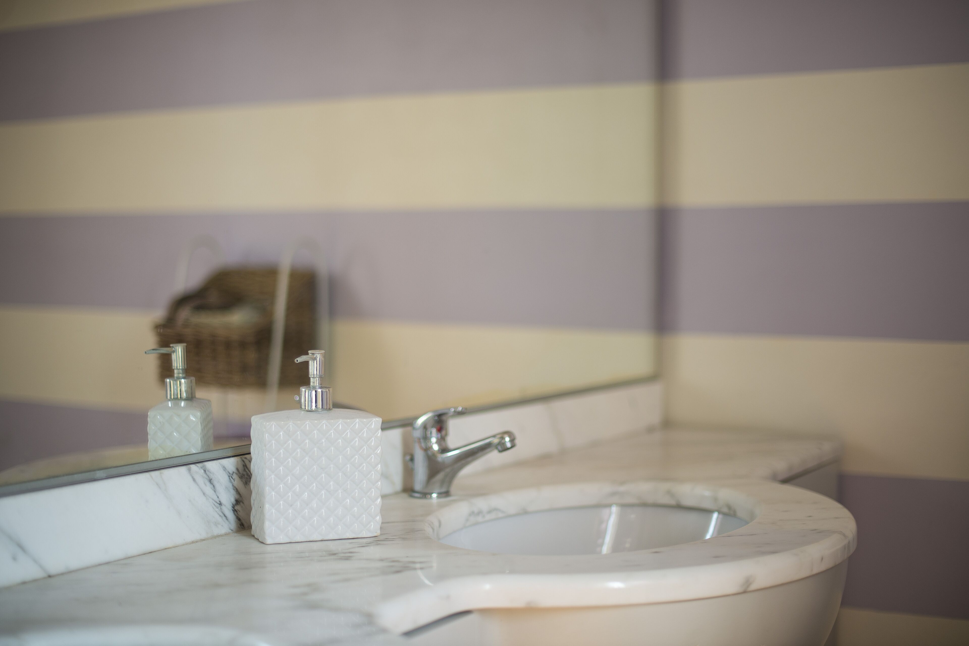 Une salle de bain avec un lavabo en marbre, un miroir et deux distributeurs de savon.