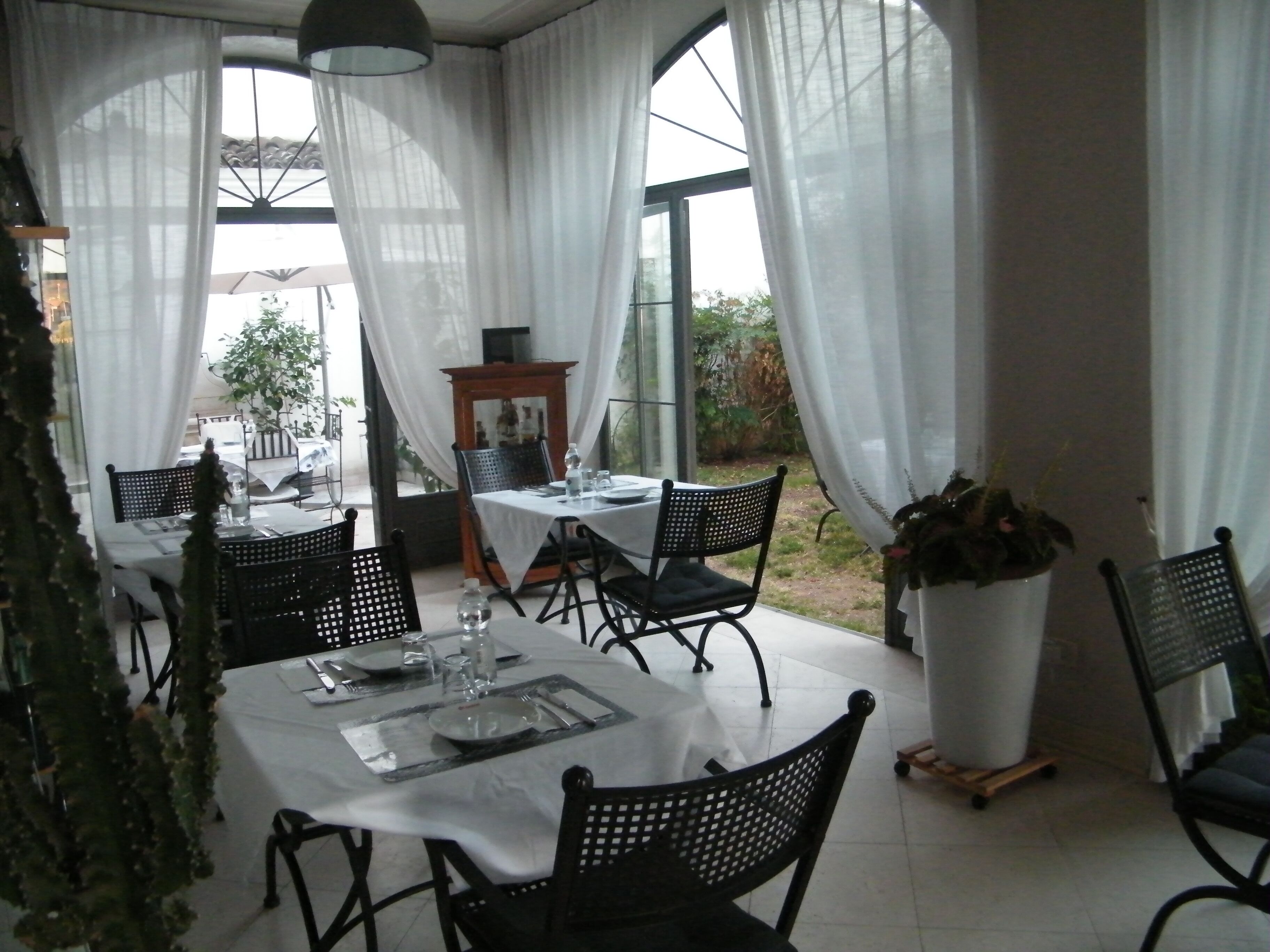 A dining area with tables set for two, featuring black chairs and white tablecloths.