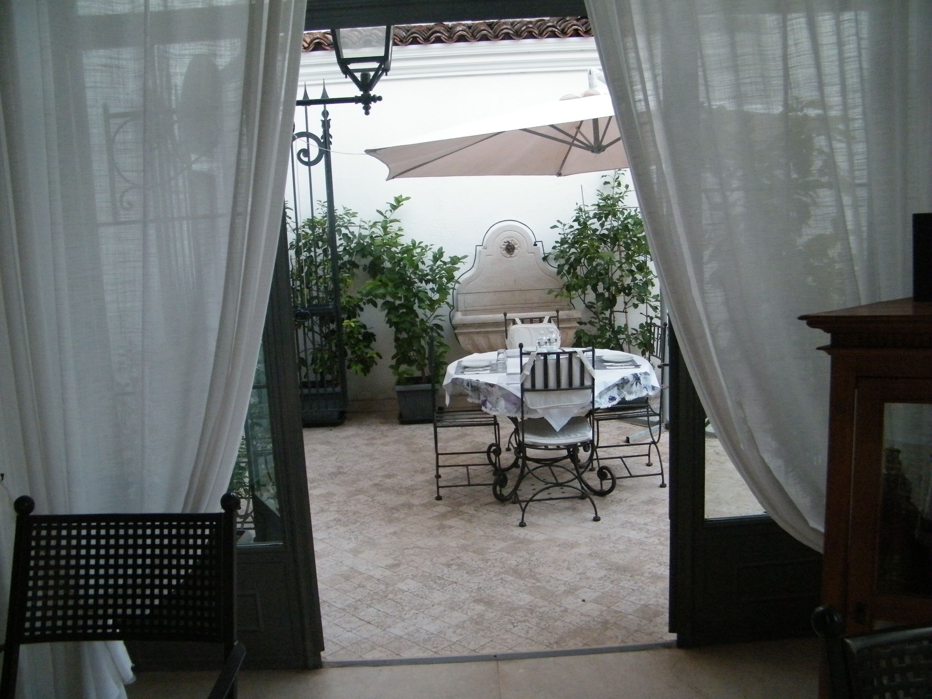 Un patio al aire libre con una mesa redonda, sillas y plantas en macetas.