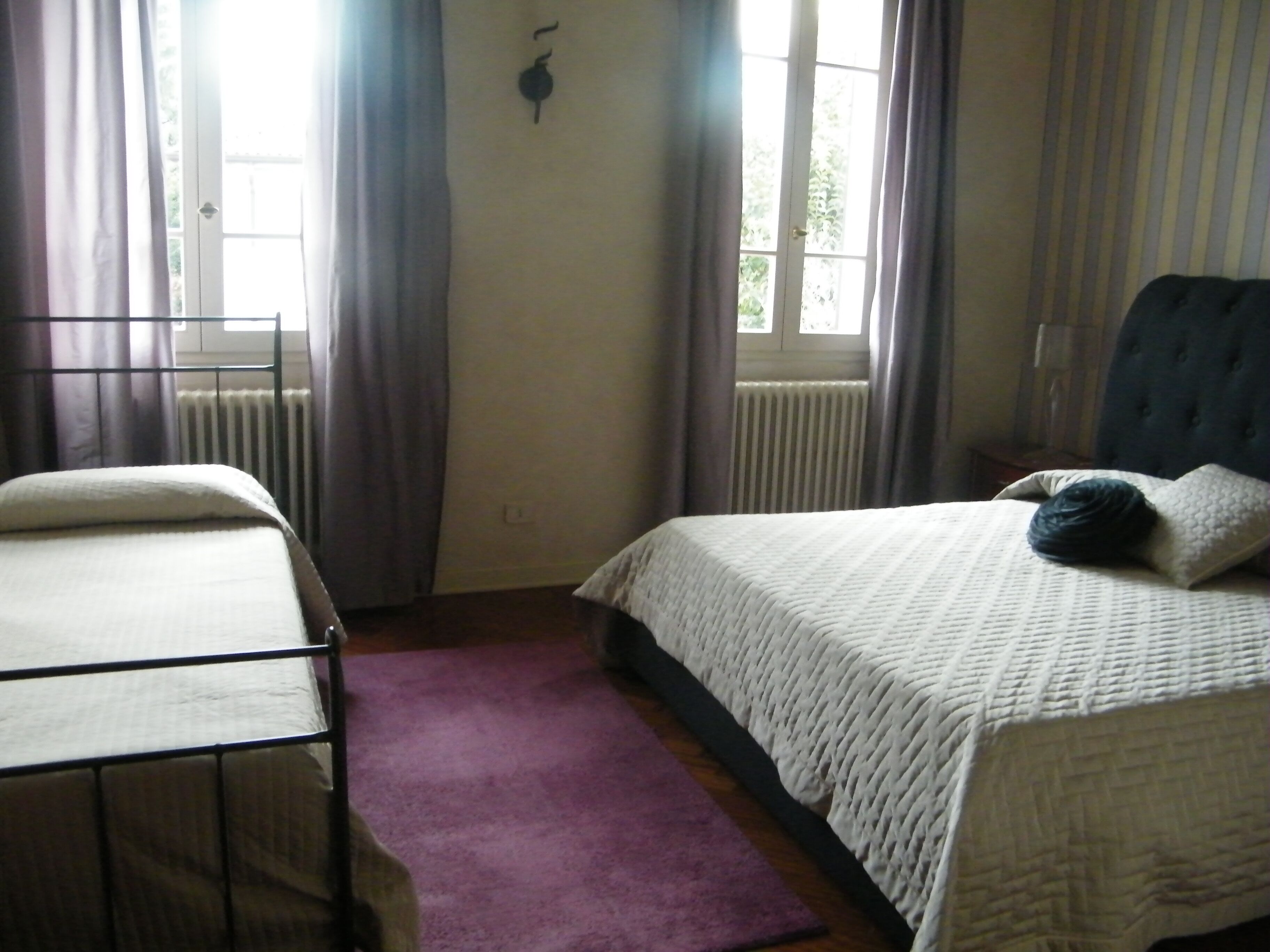 Ein Schlafzimmer mit Bett, Fenster und Heizkörper.