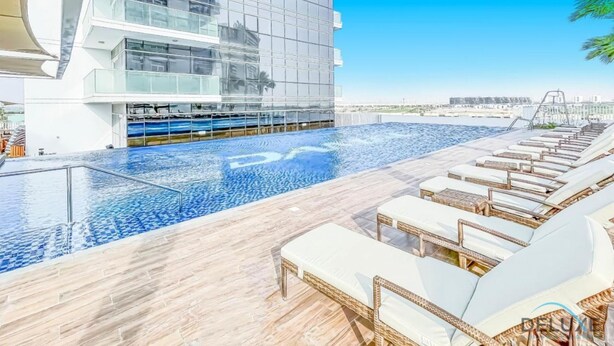 Ein modernes Hotel mit Pool auf dem Dach, Liegestühlen und freiem Blick auf die Stadtlandschaft.