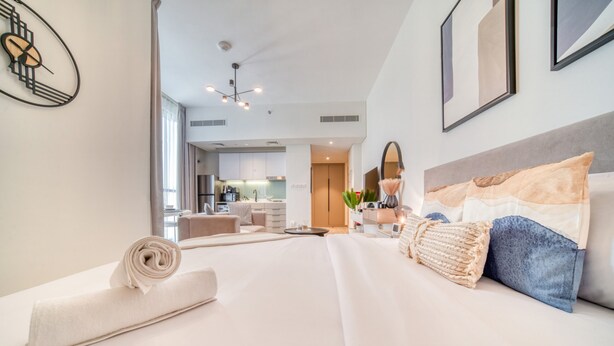 Ett modernt hotellrum med en välordnad säng, en matplats och utsikt över köket.