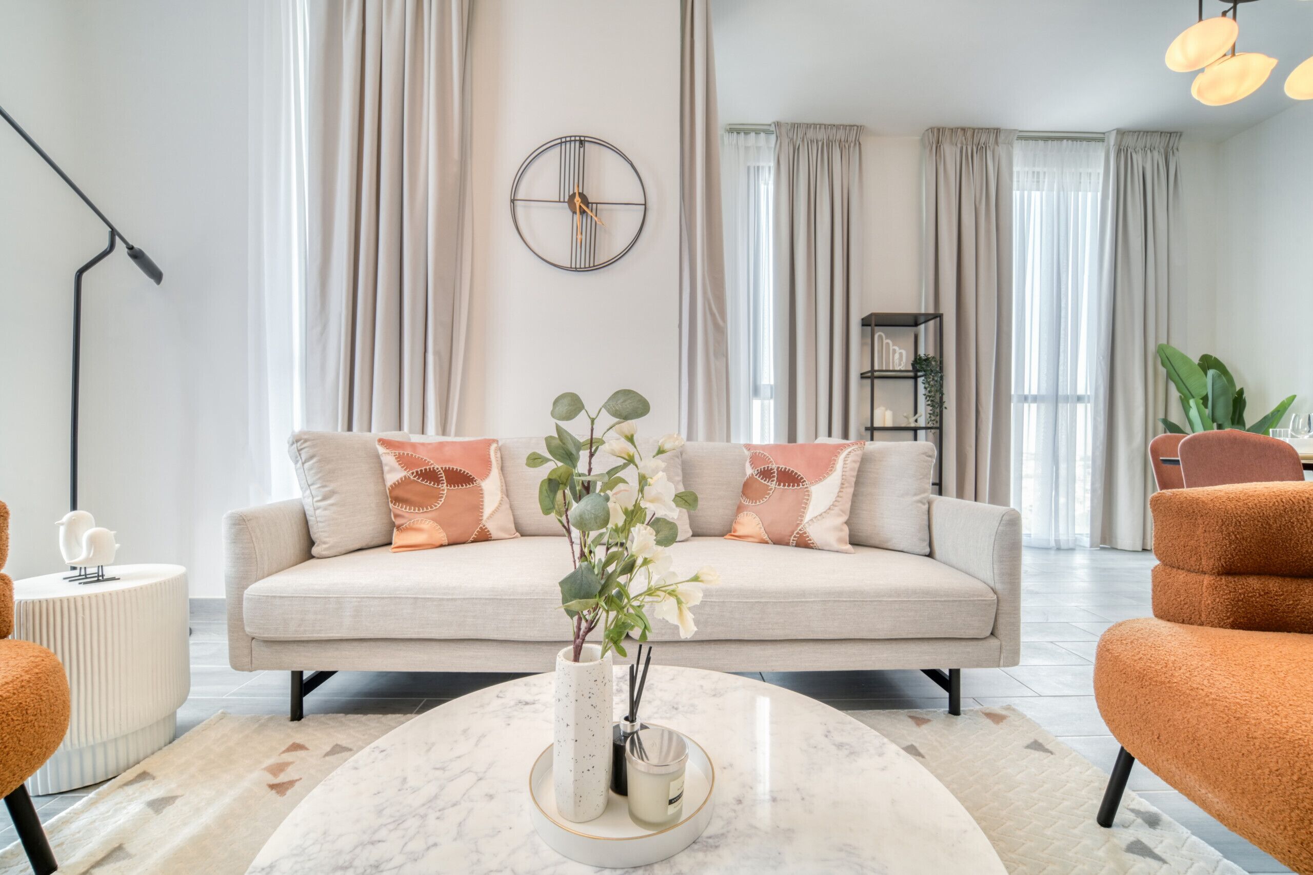 A modern living room with a beige sofa, a round coffee table, and a decorative vase with flowers.