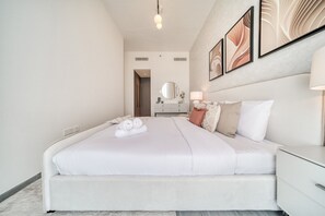 Une chambre d’hôtel moderne avec un grand lit, une table de chevet, un miroir et des œuvres d’art accrochées au mur.