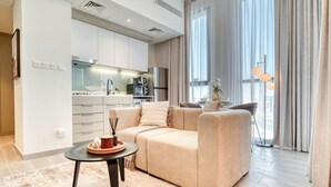 Una sala de estar moderna con un sofá, una mesa de centro y un comedor con una mesa dispuesta para dos.