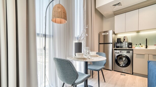 Eine moderne Küche mit Waschmaschine, Kaffeemaschine und Essbereich mit Tisch und Stühlen.