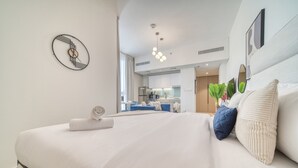 Ein modernes Hotelzimmer mit einem großen Bett, einem durch eine offene Tür sichtbaren Küchenbereich und einer einzigartigen Wanduhr.