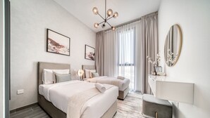 A modern hotel room with a large bed, a smaller bed, a desk, and a mirror.