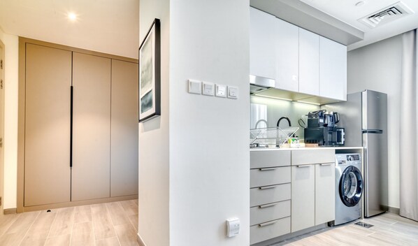 Una cocina moderna con lavadora, cafetera y refrigerador.