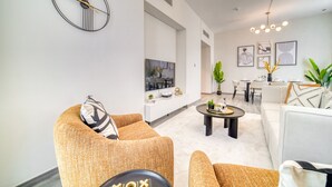 A modern living room with a sofa, coffee table, and a dining area with chairs and a table.