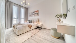 Een moderne slaapkamer met een groot bed, nachtkastjes, een spiegel en uitzicht op het groen.