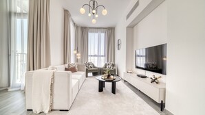 Een moderne woonkamer met een bank, fauteuils, een salontafel en een televisie.