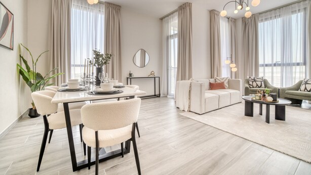 Een moderne woonkamer met een eethoek, grote ramen met gordijnen, een kroonluchter en een zithoek.