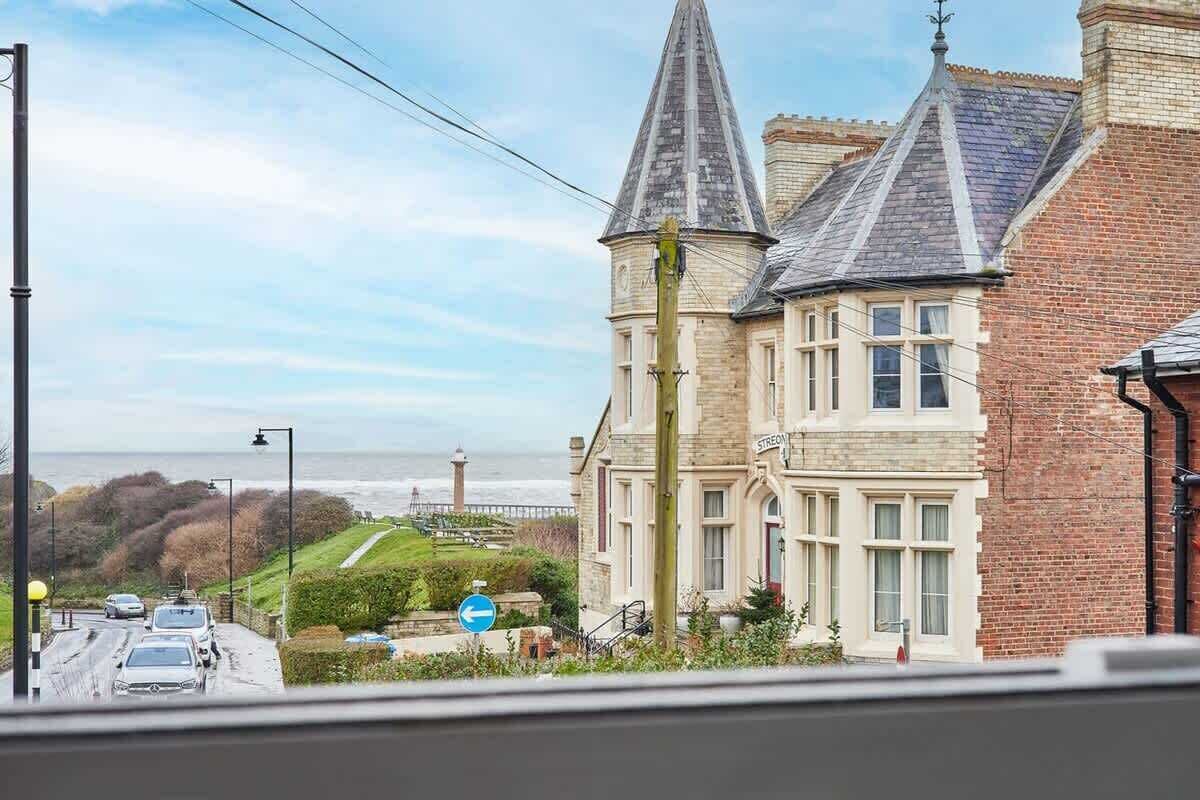 A building with a prominent tower, a brick facade, and a view of the sea.