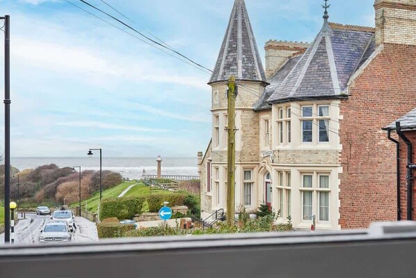 A building with a prominent tower, a brick facade, and a view of the sea. - Host & Stay | 1 The Mount (Whitby)