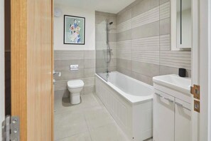 Une salle de bain moderne équipée de toilettes, d’une baignoire et d’une douche.