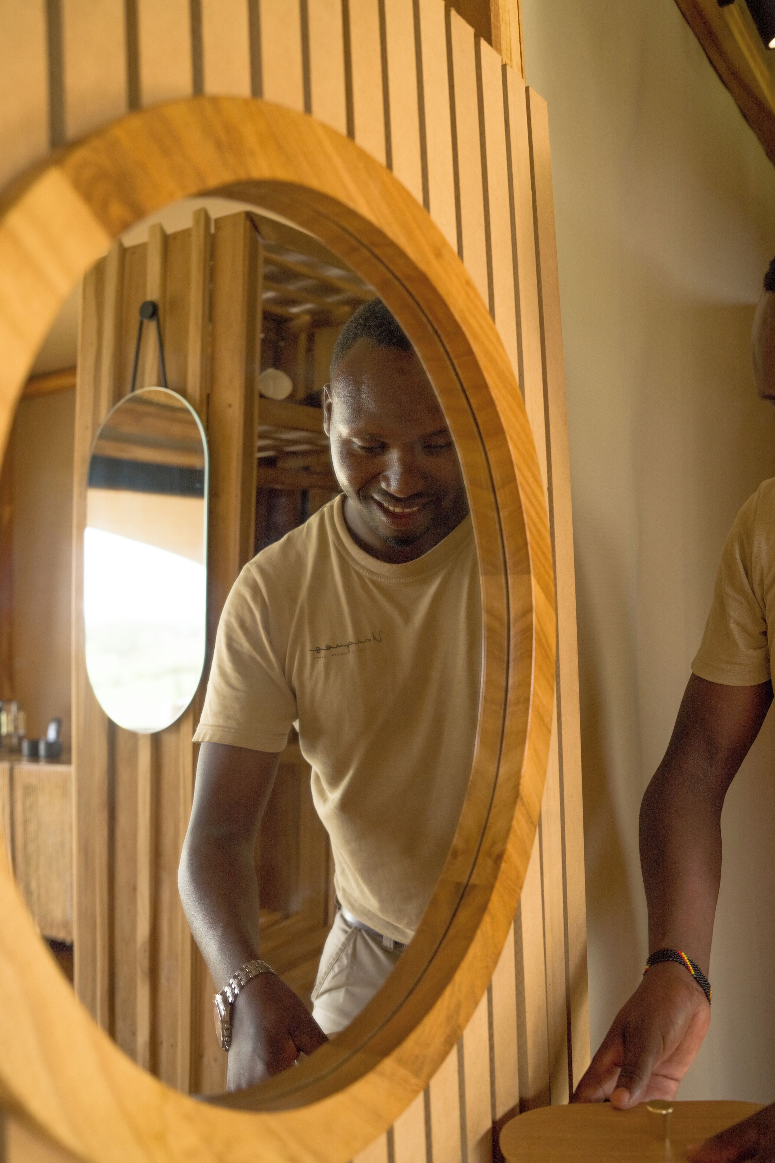 Un miroir à cadre en bois, avec une personne debout devant.