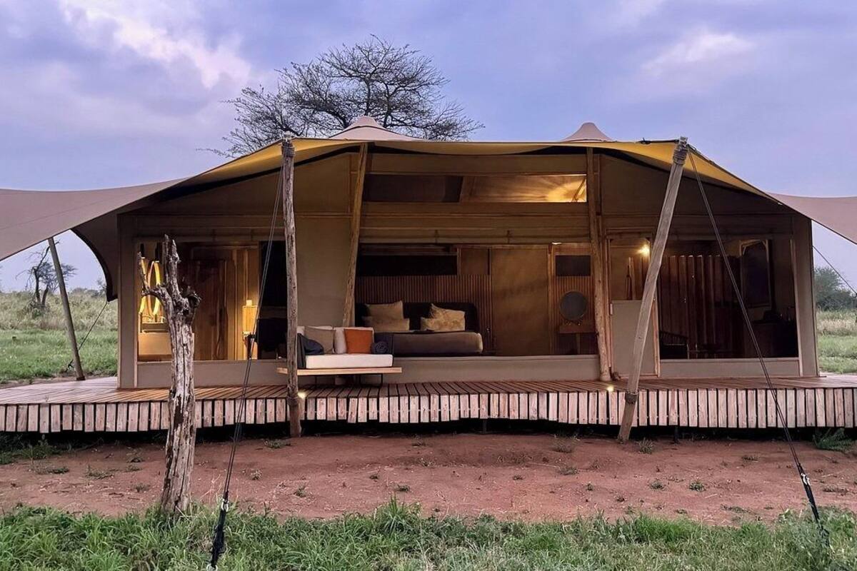 Una tienda safari con cama, almohadas y una pequeña mesa.