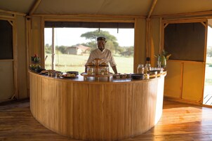 Uma bancada de madeira com um chef em pé atrás dela, cercado por diversos alimentos e utensílios de cozinha.