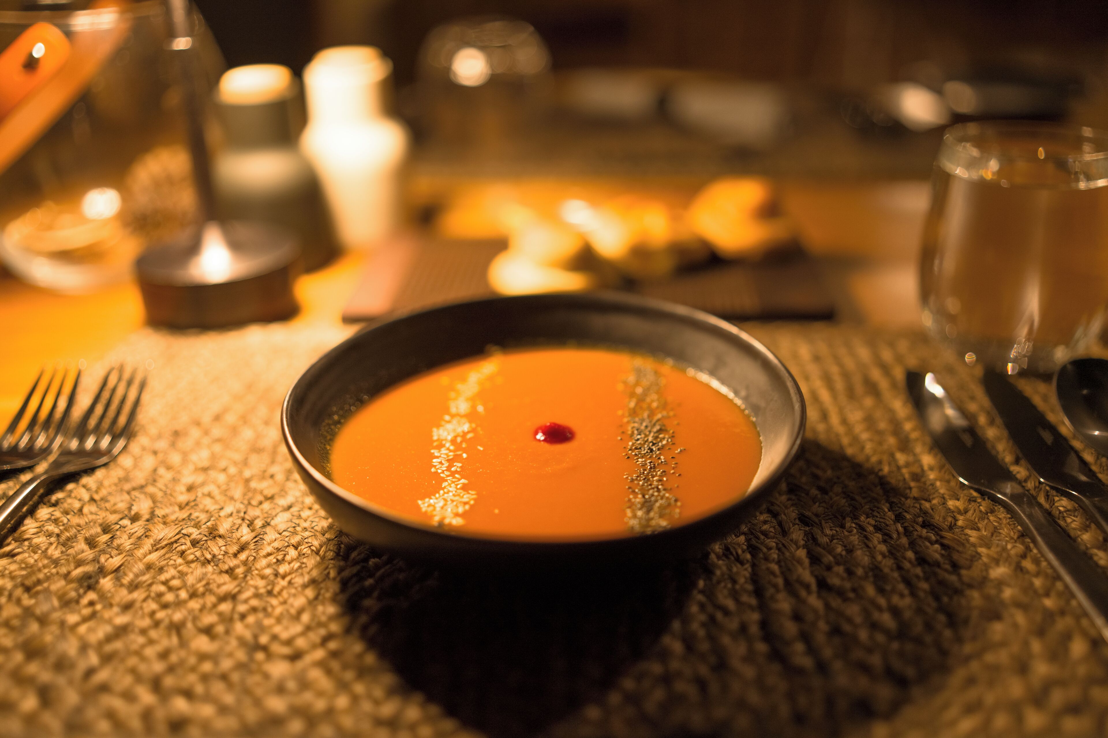 A bowl of soup with a garnish on a textured tablecloth.