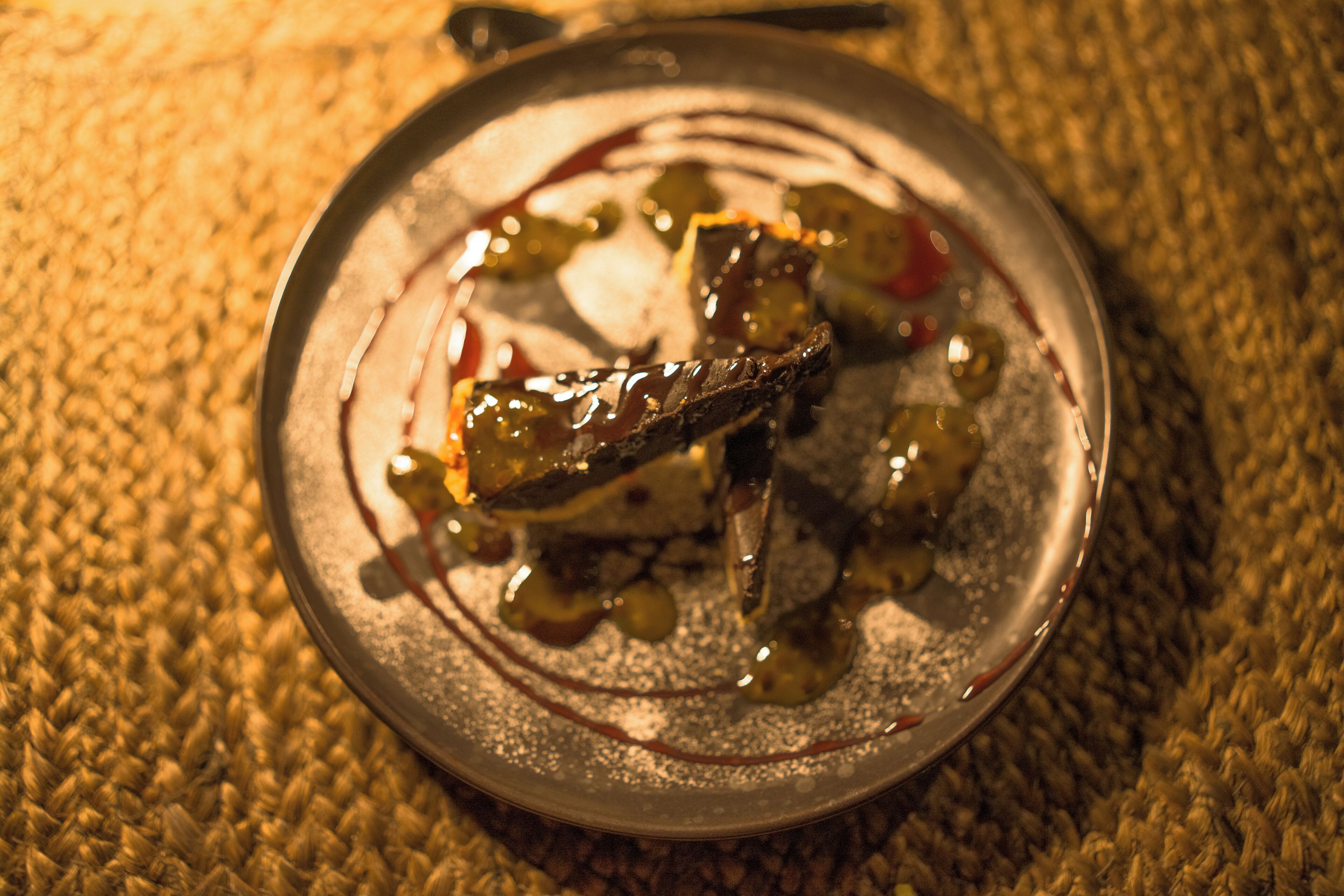 Une assiette contenant des légumes grillés et une sauce, le tout disposé sur une surface texturée.