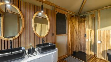 A modern bathroom with wooden paneling, a double sink, and a glass shower enclosure.