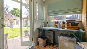 A room with a large window, a desk with various items, a wicker basket, and a framed picture of a dog. - Chichester Lodge -  a cottage that sleeps 8 guests  in 4 bedrooms (Chichester)