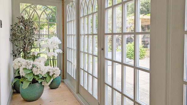 A hallway with large arched windows and two potted plants with white flowers. - Chichester Lodge -  a cottage that sleeps 8 guests  in 4 bedrooms (Chichester)