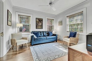 A living room with a blue sofa, two armchairs, a coffee table, and a ceiling fan.