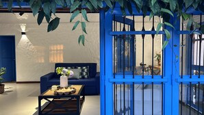 Una stanza con una porta blu, un divano, un tavolino da caffè con un vaso e piante pensili.