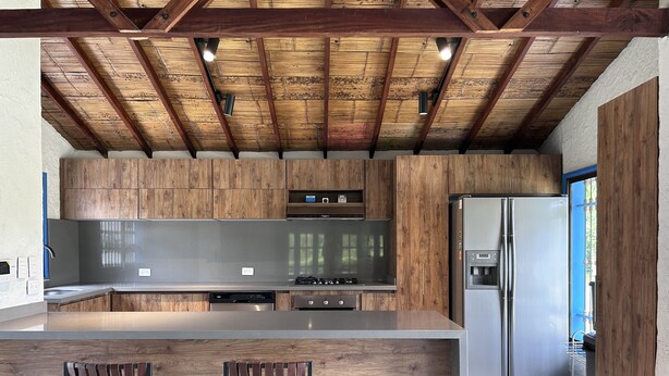 Una cucina moderna con mobili in legno, elettrodomestici in acciaio inossidabile e un'area bar con sgabelli.