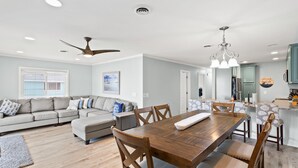 Un salon spacieux avec une table à manger en bois, un canapé et un ventilateur de plafond.