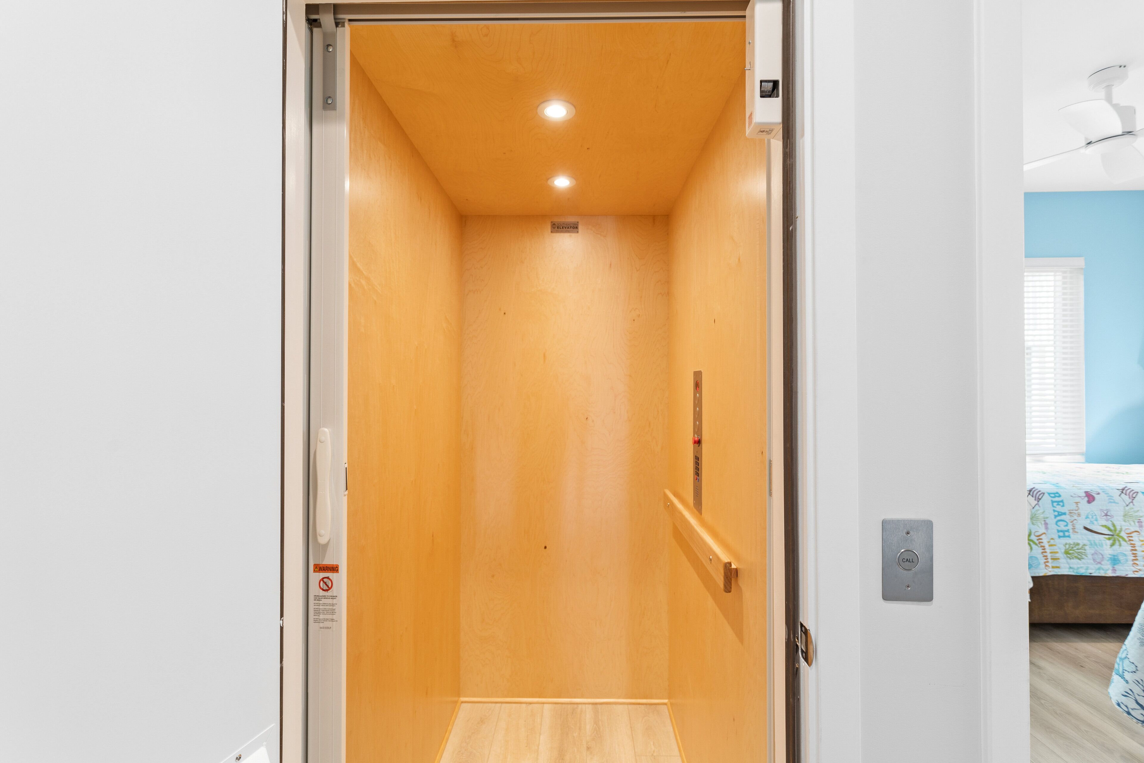 Een smalle lift met houten wanden en een metalen handgreep.