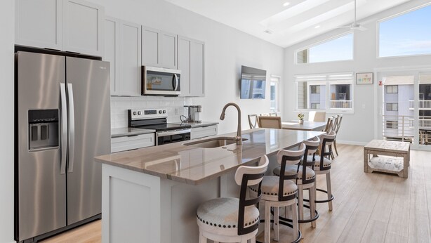 A modern kitchen with a central island, stainless steel appliances, and a dining area with bar stools.