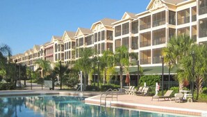 Ein Hotel mit mehreren Balkonen, einem Swimmingpool und Palmen.