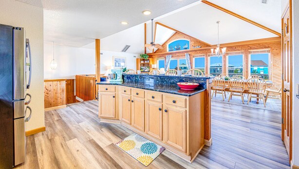 A spacious kitchen with wooden cabinets, a large island, and a view of the ocean through large windows. - Semi-Oceanfront Dog Friendly w/ Pool, Hot Tub, Cargo Lift, Nearby Beach Access (Salvo)