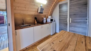 Une cuisine compacte avec des meubles en bois, un évier, un four à micro-ondes et une machine à café.