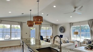 A modern kitchen with a large island, pendant lights, and a ceiling fan. - Seaspray | Private Pool + 4 Bikes (Miramar Beach)