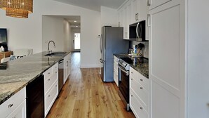 A modern kitchen with white cabinets, a granite countertop, and a stainless steel refrigerator. - Seaspray | Private Pool + 4 Bikes (Miramar Beach)