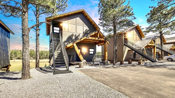 Eine moderne Lodge mit markantem architektonischen Design, bestehend aus einem zentralen Gebäude mit auffälliger Treppe und einem Anbau.