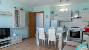 A modern kitchen with a dining area, a TV, and a sofa. - Stella Marina apartment, vacation home in Trapani, a few steps from the sea  (Trapani)