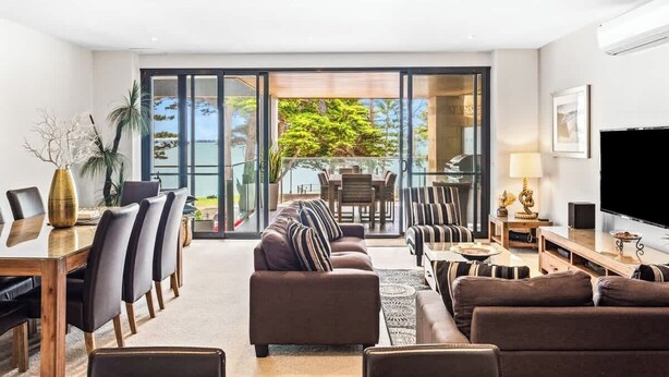 Una sala de estar moderna con comedor, ventanas amplias y televisor de pantalla plana.