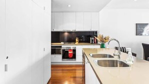 Una cocina moderna con armarios blancos, un lavamanos de acero inoxidable y un horno empotrado.