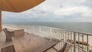 Ein Balkon mit Korbmöbeln und Blick auf den Strand.