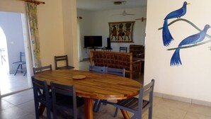 A dining area with a wooden table and chairs, a television, and a wall with a bird painting.