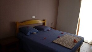 A bed with a wooden headboard, a blue bedspread, and a decorative pillow.