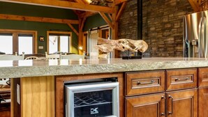 Una cocina amplia con vigas de madera, pared de piedra y refrigerador de acero inoxidable empotrado.