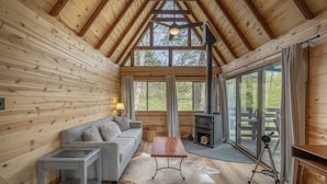 Interior acogedor de una cabaña con paredes de madera, un sofá, una mesa y una chimenea.